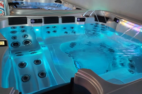 Modern hot tub display with illuminated blue water and control jets in showroom