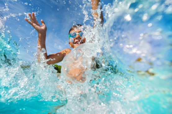 Child splashing joyfully in a family pool with clear blue water