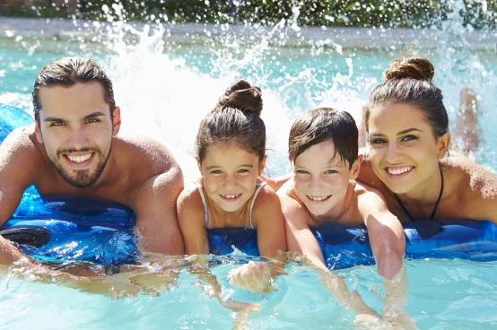 Happy family enjoying their residential swimming pool together on a sunny day