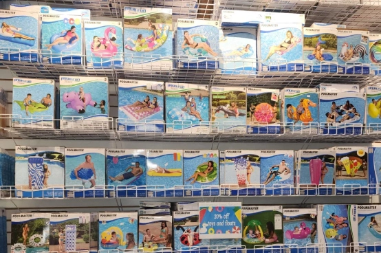 Colorful pool floats and inflatable accessories displayed on retail shelves at pool supplies store