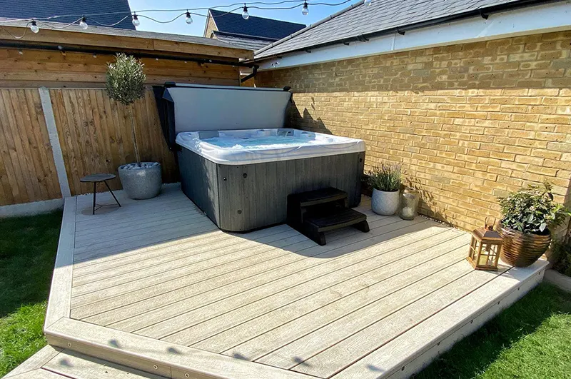 Modern backyard hot tub spa installed on composite deck with wooden privacy fencing